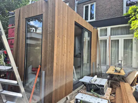 De houten aanbouw vanaf de tuin, met de schuifpui open naar de keuken