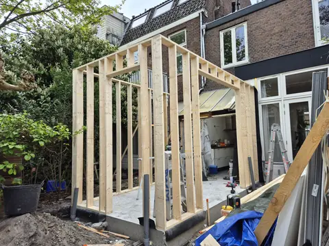 Het houtskelet van de aanbouw op de nieuwe fundering, nog zonder gevelbekleding