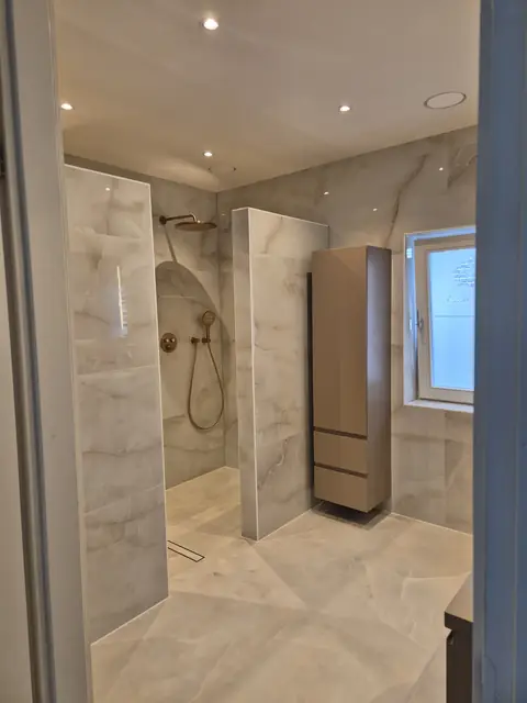 De badkamer richting het raam, met de lage wandkast en de douche op de voorgrond