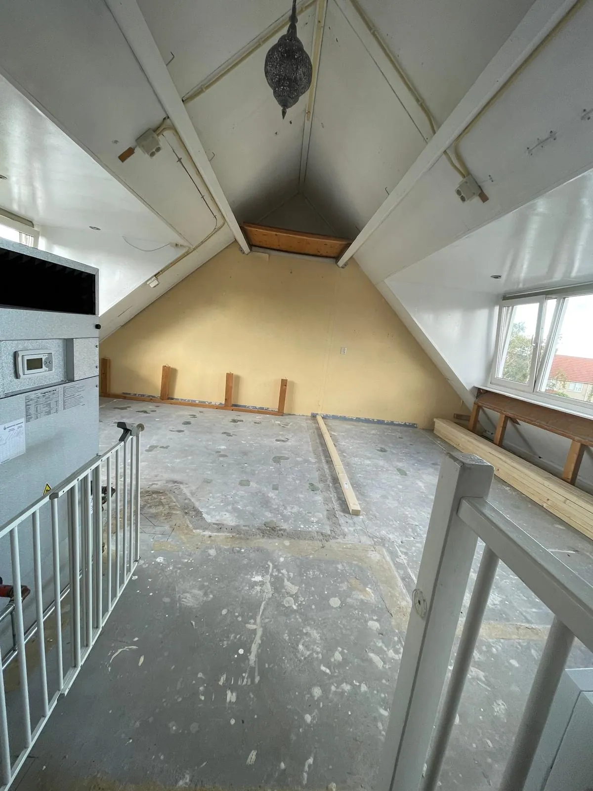 Voor de verbouwing: De kale zolder voor de verbouwing, met gestripte vloer en een gele wand